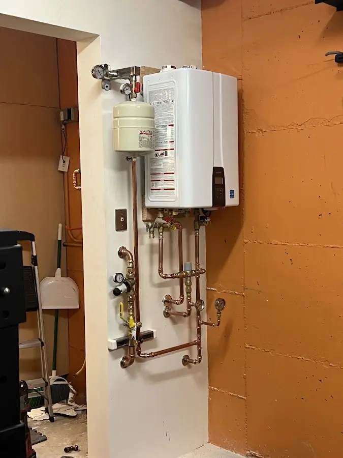 Plumbing technician inspecting water heater connections in Tarrant